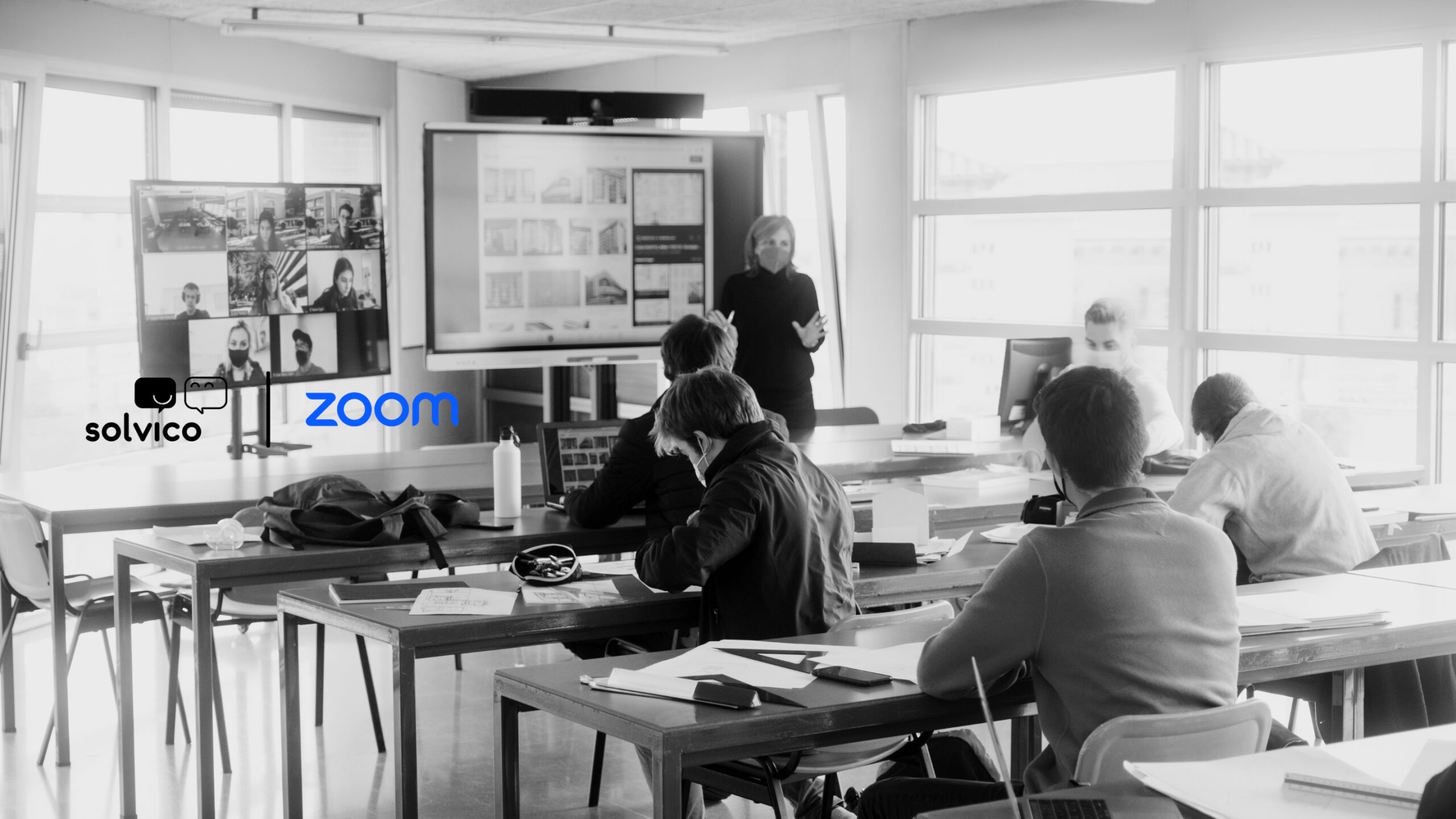 Aula digitalizada en Universidad La Salle con clase híbrida usando Zoom, con logos de Zoom y Solvico visibles.
